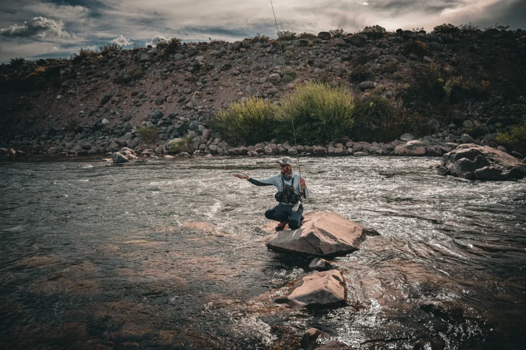 Angler crouching in a rapid, fly fishing in northern Patagonia