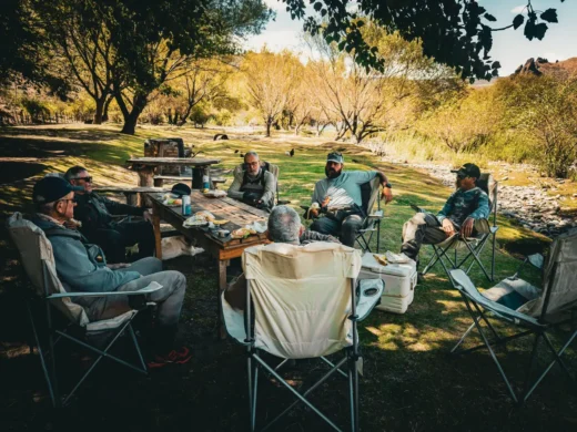 Anglers resting in camp chairs under the trees between sessions