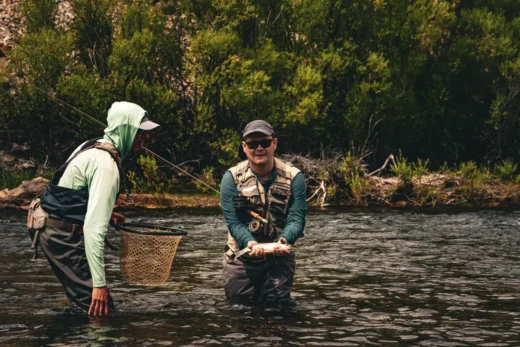Guide netting a trout for a client in the current