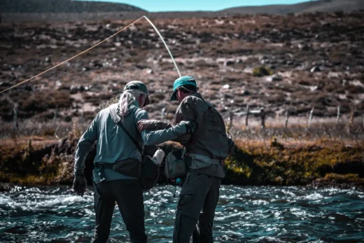 Angler fighting a fish in fast water with the guide alongside