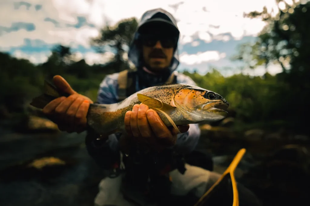 Bearded guide holding a brown trout under a dramatic Patagonian sky