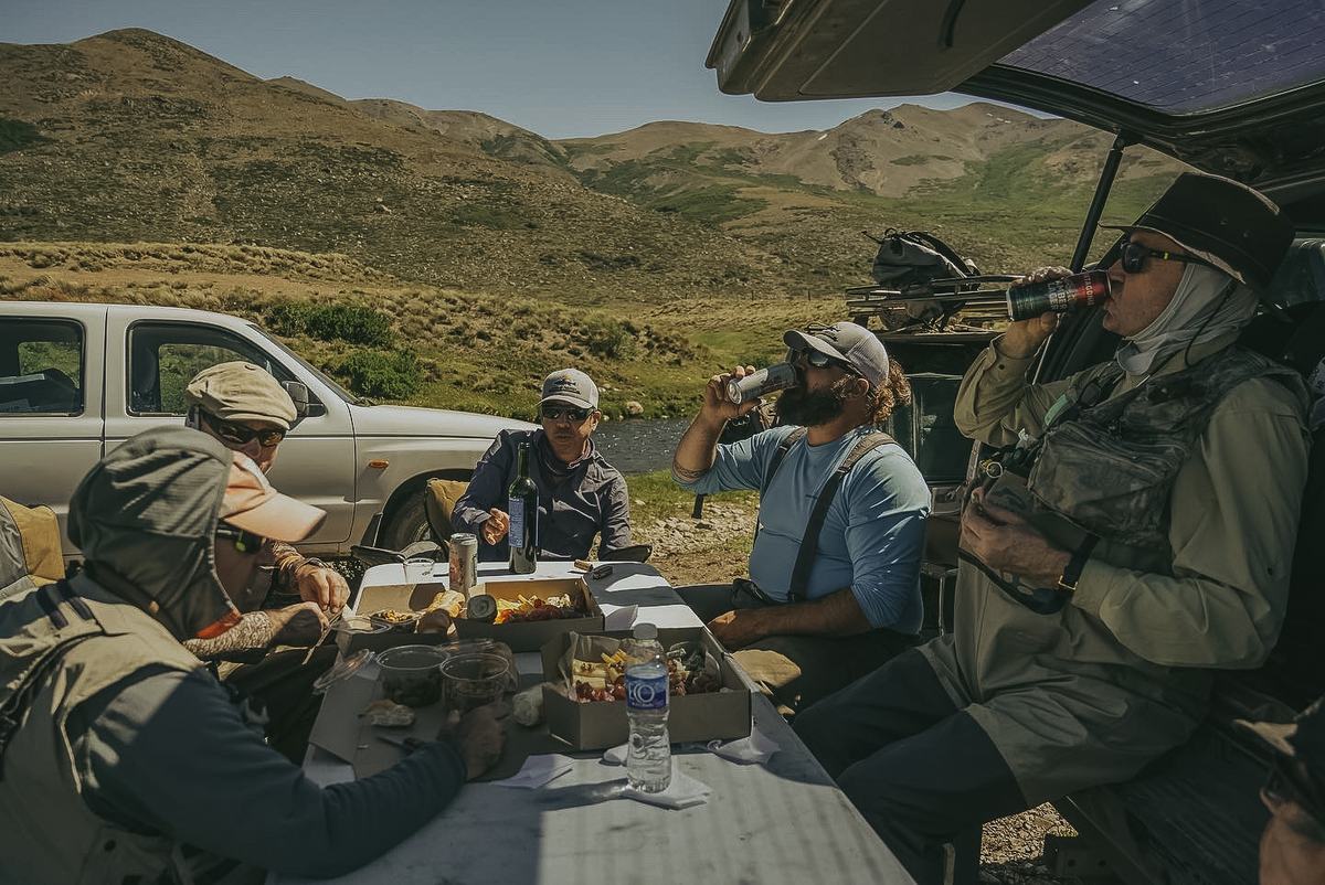 Anglers and guides having lunch beside the trucks on the steppe in northern Neuquén